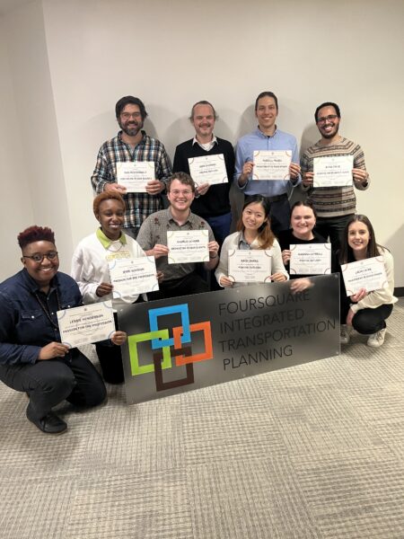 Staff holding certificates and smiling into camera.